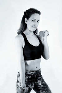 Portrait of smiling young woman standing against white background