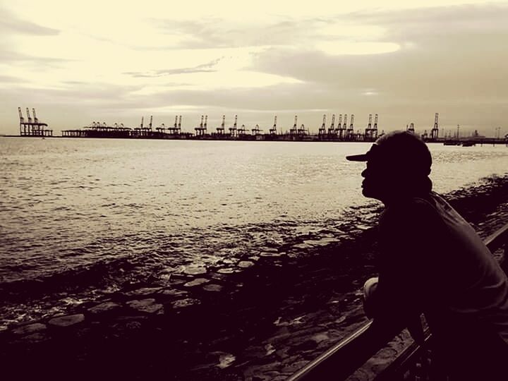 WOMAN STANDING ON SHORE AGAINST CITYSCAPE DURING WINTER