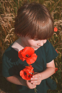 Close-up of boy holding red flowering plant