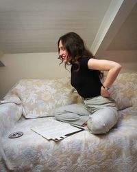 Young woman sitting on bed at home