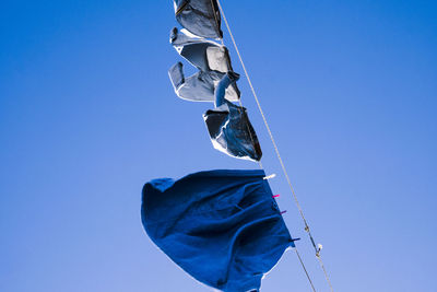 Low angle view of laundry hanging on clothesline against clear blue sky