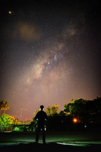 Rear view of silhouette man standing against sky at night