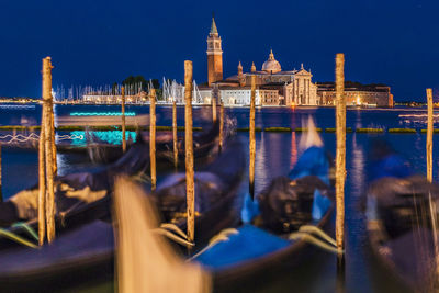 Illuminated city by canal at night