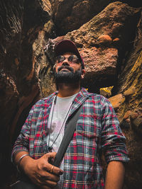 Portrait of man standing against rock