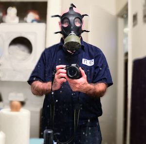 Man wearing gas mask while photographing through camera