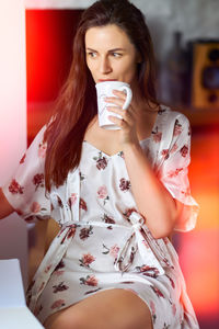 Young woman using mobile phone while sitting at home