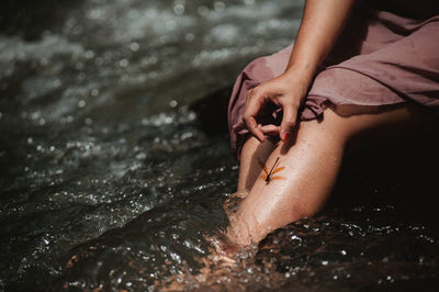 Midsection of woman sitting at riverbank