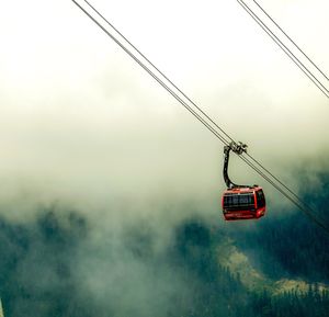 Low angle view of overhead cable car against sky