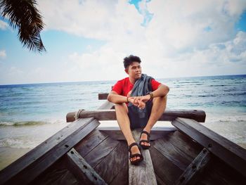 Full length of young man sitting on boat at beach