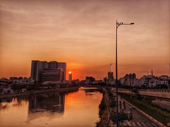 River amidst buildings against sky during sunset