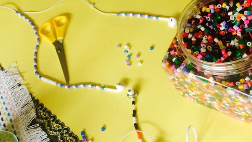 High angle view of headphones with beads on yellow table