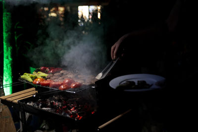 Close-up of person preparing food on barbecue grill 