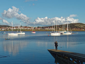 Boats moored at harbor against sky