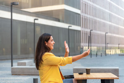 Young woman standing against yellow wall in city