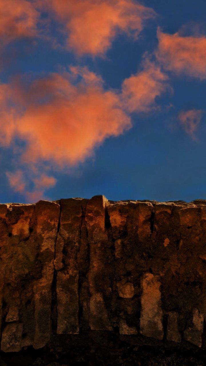 LOW ANGLE VIEW OF CLIFF AGAINST CLOUDY SKY