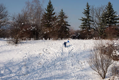 Happy child climbing ob a snow slide in the park