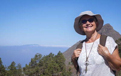 Portrait of smiling woman standing on mountain against sky