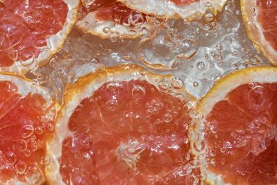 Slices of blood red ripe grapefruit in water. close-up slices of red grapefruit on white background