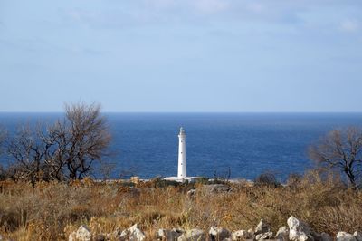 Lighthouse by sea against sky