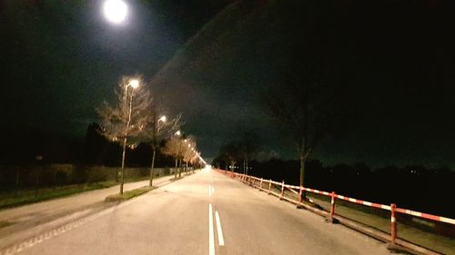 Illuminated road against sky at night