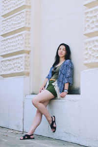 Portrait of young woman standing against wall