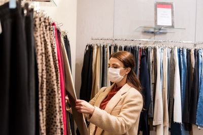 Woman wearing mask while looking at garments