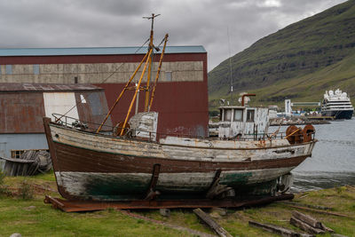 Old boat moored on beach against sky