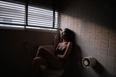 Woman smoking cigarette in bathroom