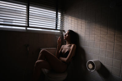 Woman sitting on wall at home