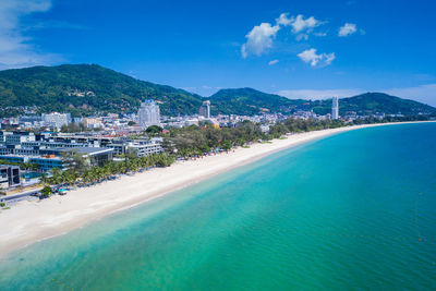 Scenic view of sea by city against blue sky