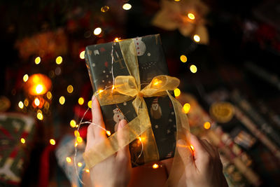 Close-up of hand holding illuminated christmas lights