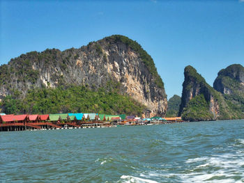 Scenic view of sea and mountains against clear blue sky