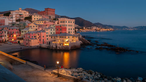 Buildings by sea against sky at dusk