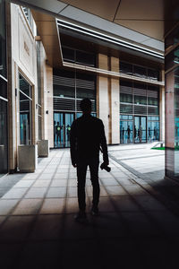 Rear view of man walking on footpath against building