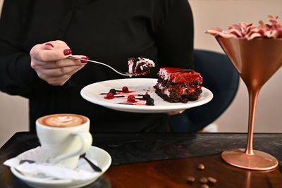 Midsection of man holding ice cream on table