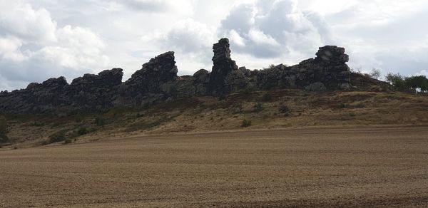 Rock formations on field against sky