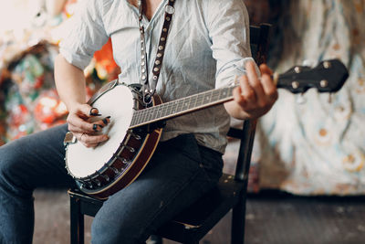 Midsection of man playing guitar