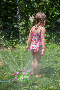 Girl standing by sprinkler in garden