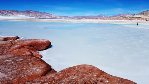 Scenic view of salt flat by mountain against sky