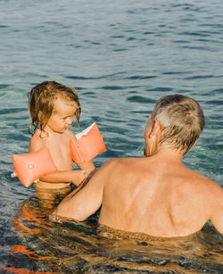 Rear view of mother and daughter in swimming pool