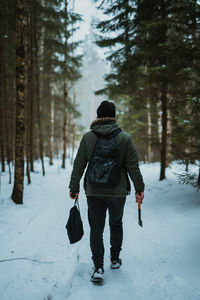 Rear view of man walking on snow covered land