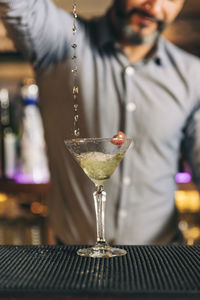 Midsection of bartender preparing cocktail in bar