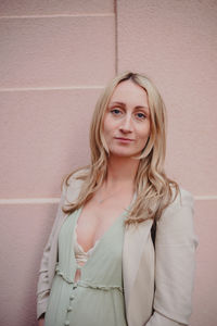 Portrait of young woman standing against wall