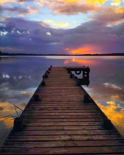 Wooden pier on lake against cloudy sky