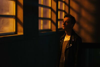 Thoughtful man standing by window in darkroom