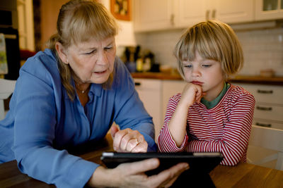 Boy looking at grandmother using digital tablet