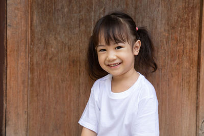 Portrait of cute girl sitting against wall