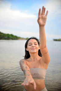 Beautiful woman meditating against lake