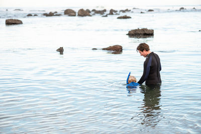 Father helping young child learn to snorkel