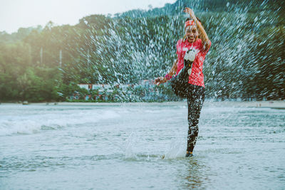 Full length of woman splashing water in rain